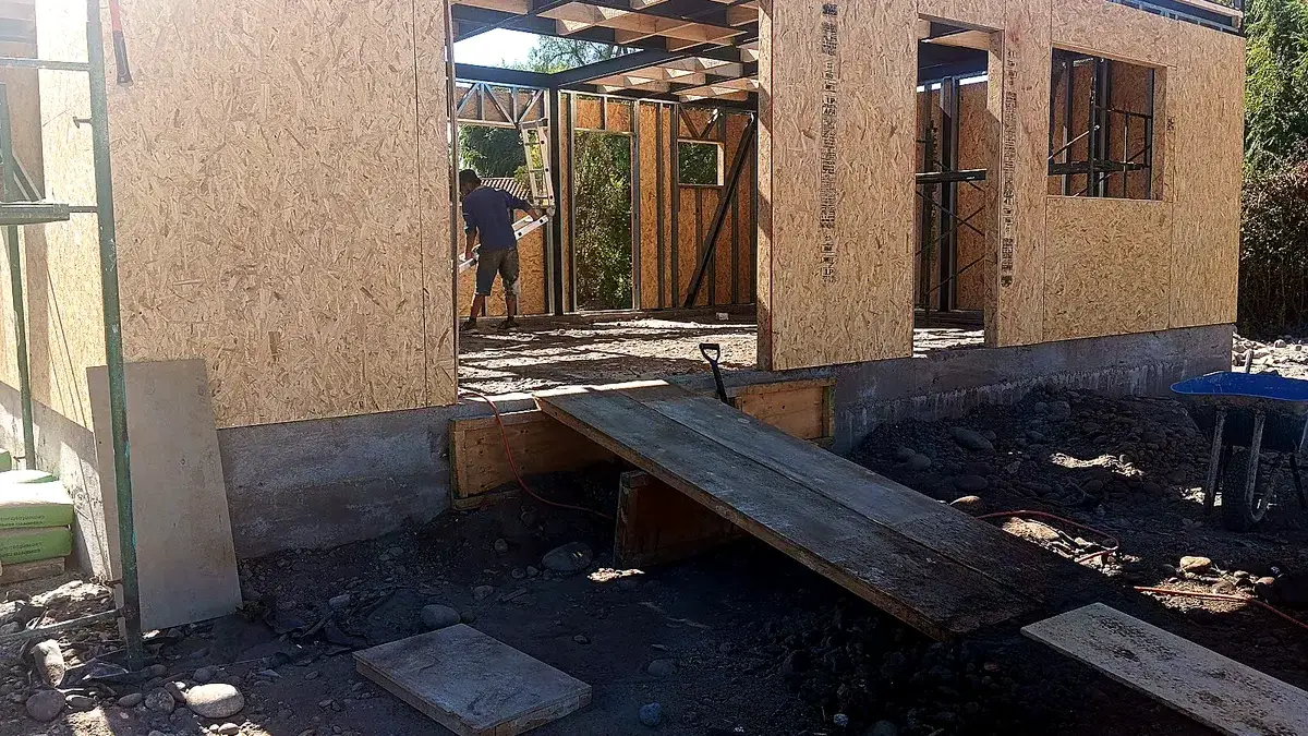 Entramado de un piso superior en construcción, con un trabajador y una rampa de acceso a la obra.