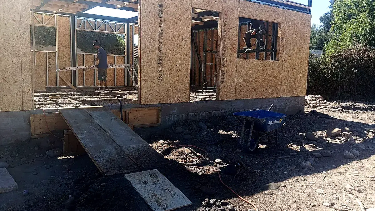 Entramado interior de una vivienda en construcción: montantes de la estructura antes de revestir, con un trabajador en obra.