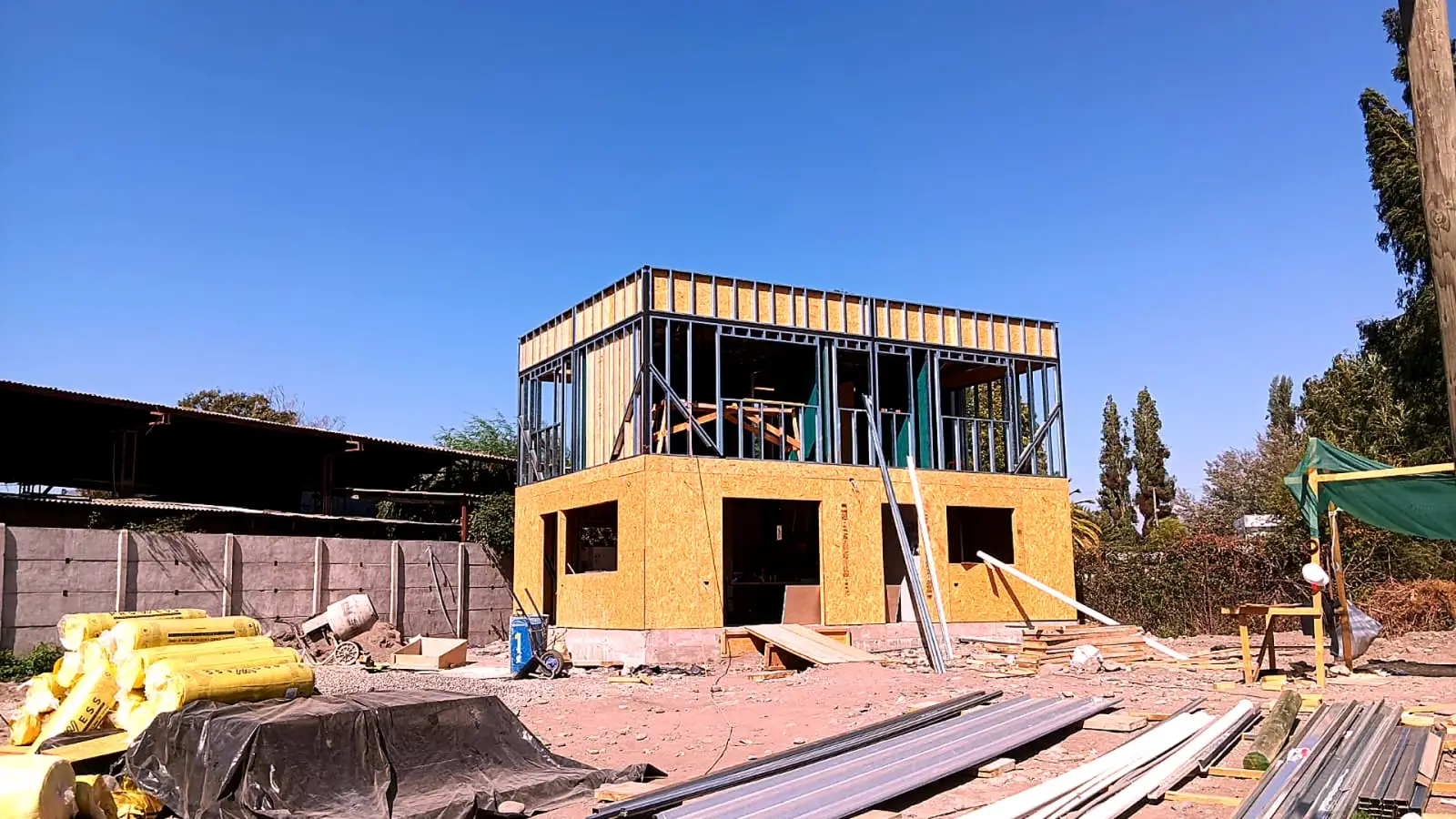 Casa de dos pisos en construcción con estructura liviana de acero y madera, revestida con paneles OSB