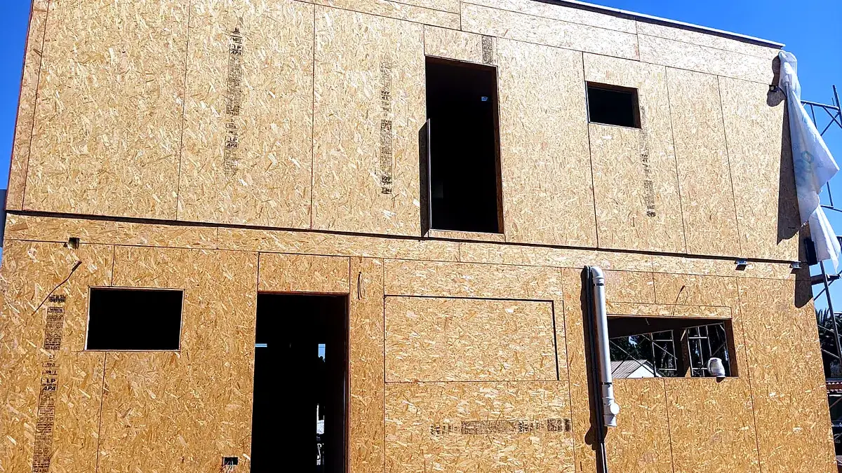 Muros de una casa revestidos con paneles OSB durante la construcción, con las aberturas de puertas y ventanas ya definidas.