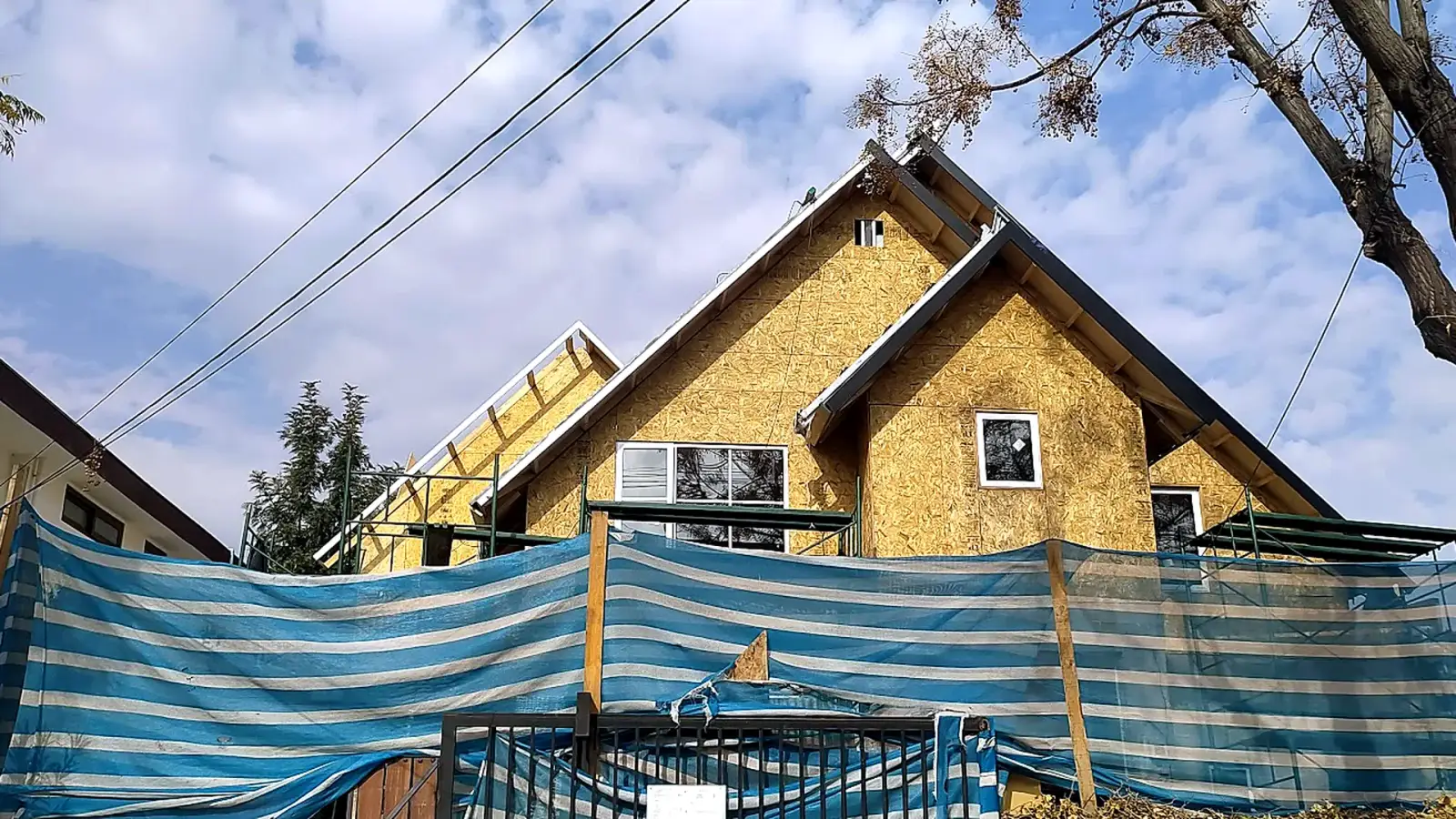 Casa de dos pisos en construcción vista de frente, con techumbre a dos aguas y revestimiento OSB