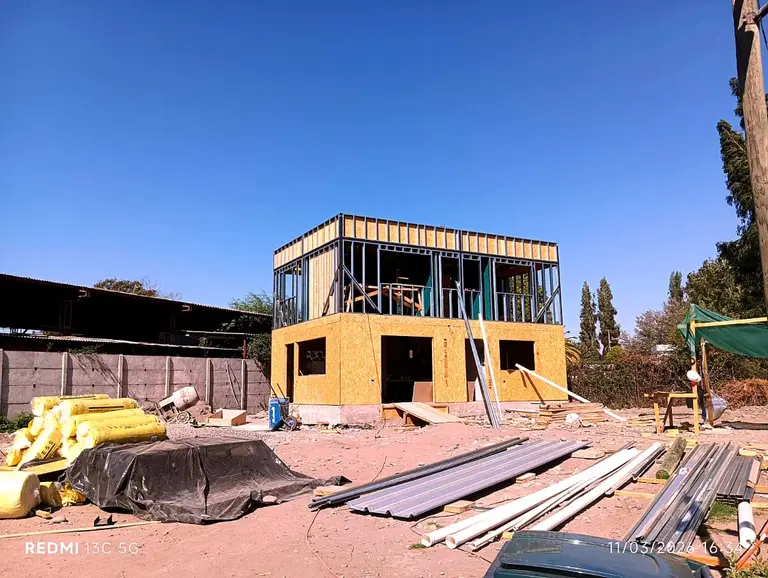 Casa de dos pisos en construcción con estructura y revestimiento en avance